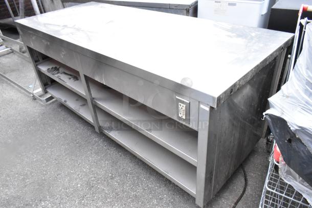 Stainless steel table with two under shelves and commercial casters. Features a power outlet, suitable for kitchen use.