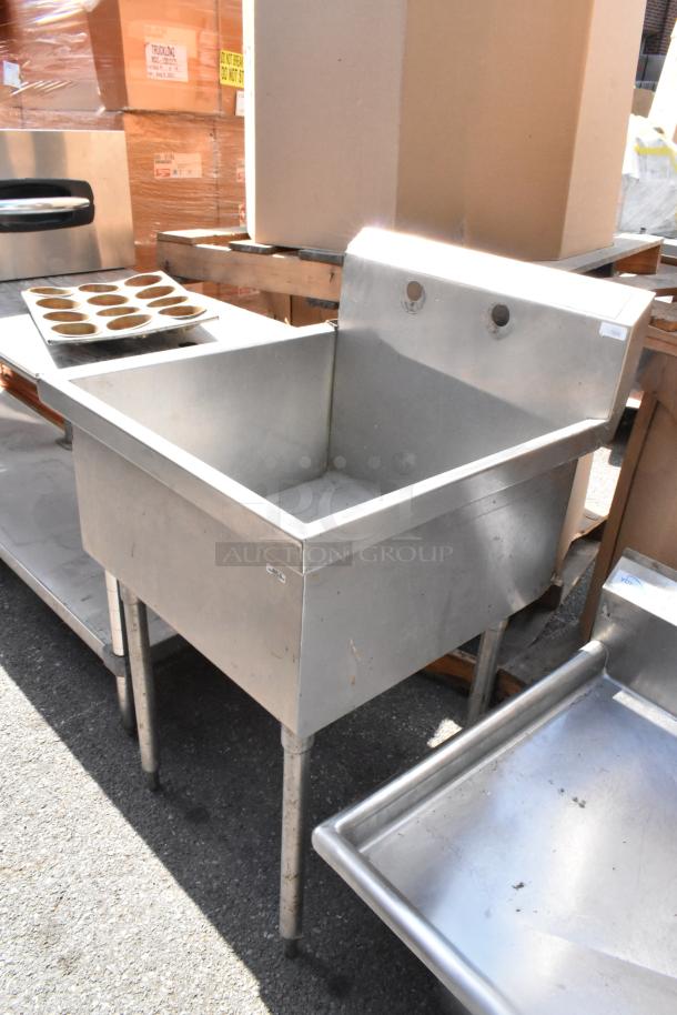 Stainless steel single bay sink with backsplash, showing signs of wear. Ideal for commercial kitchen use. No visible tags.