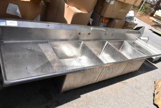 Stainless steel 3 bay sink with dual drain boards, no legs, in used condition. Marked with inventory tag.