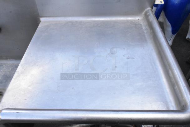 Stainless steel single bay sink with right side drain board, showing wear. Ideal for commercial use.