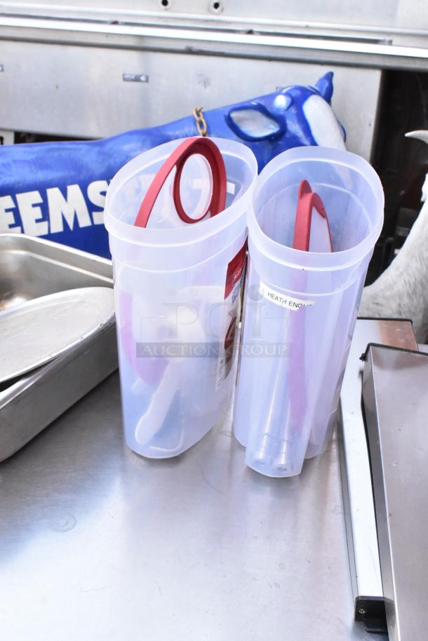 Stainless steel table with under shelf, containing utensils in plastic containers; visible “Heath English” label.