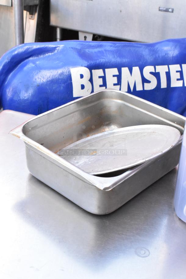 Stainless steel table with under shelf. Includes a metal pan with lid and "BEEMSTER" marked blue wrapping. Light wear evident.