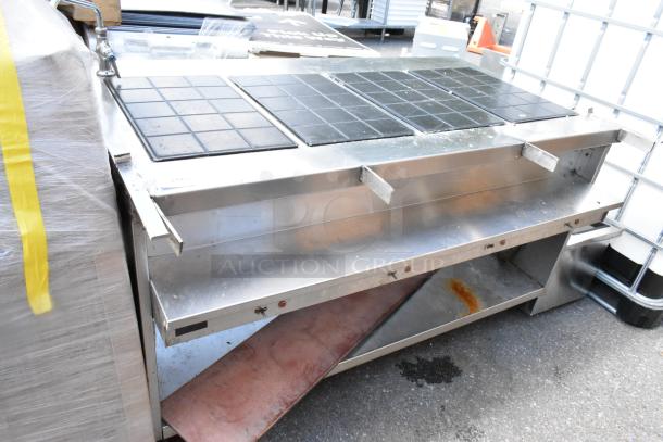 Stainless steel commercial warming table with tiled top, open shelf below, signs of wear and rust.