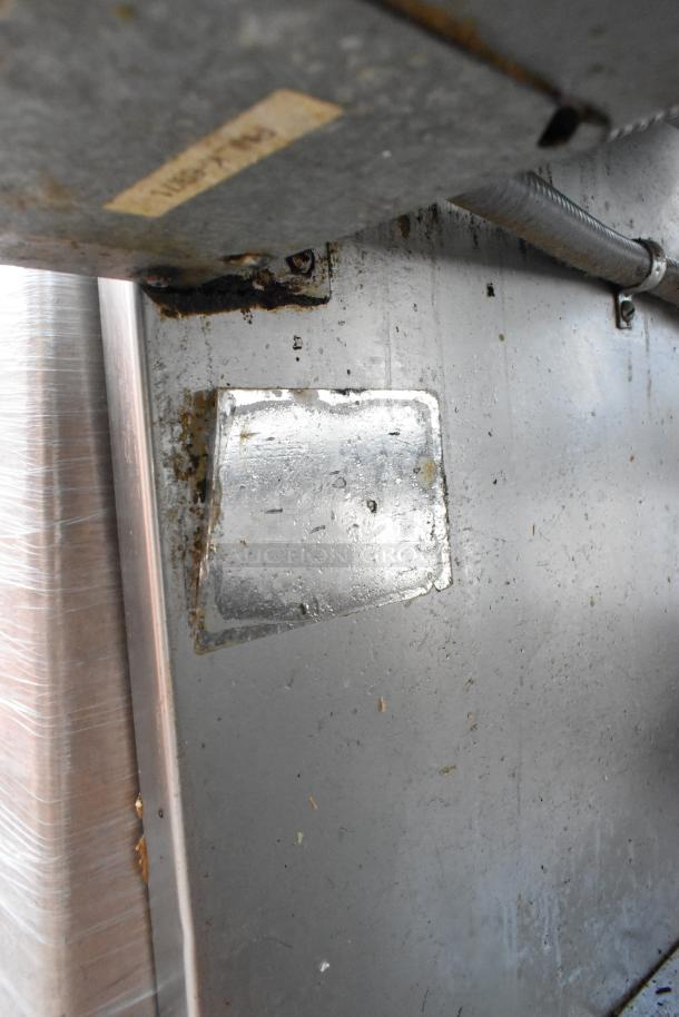 Stainless steel commercial warming table, showing underside with visible label holder and signs of wear, in used condition.