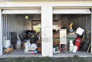Storage unit with stroller, children's furniture, toys, vintage popcorn cart, Everlast punching bag, tire, rocking chair, lawnmower.