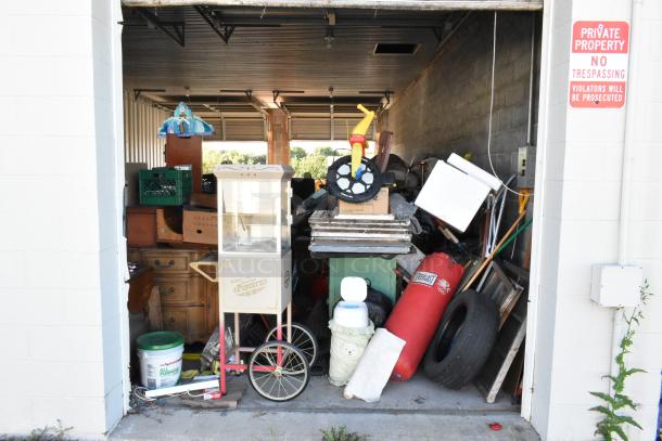 Storage unit contents: stroller, children's furniture/toys, white vintage-style popcorn cart, Everlast punching bag, tire, rocking chair, lawnmower.