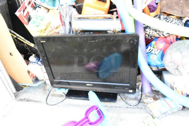 Storage unit contents including a Sony TV, mini cooler, children's toys, and baskets. Unit appears cluttered.