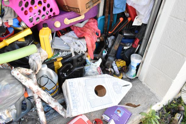 Storage unit contents with mini cooler, Sony TV, children's toys, baskets, and cleaning supplies. Items cluttered and varied.