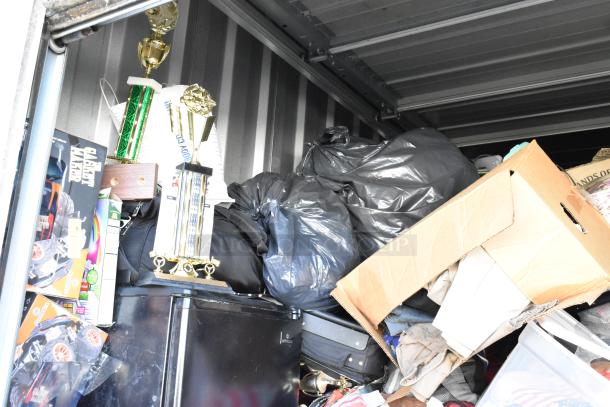 Storage unit contents including mini cooler, Sony TV, toys, trophies, and boxes. Items in varied conditions.