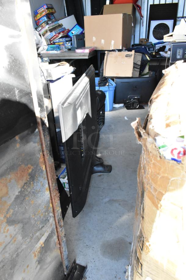 Storage unit with various items including board games, boxes, a portable grill, and electronics. Items must be cleared for deposit return.