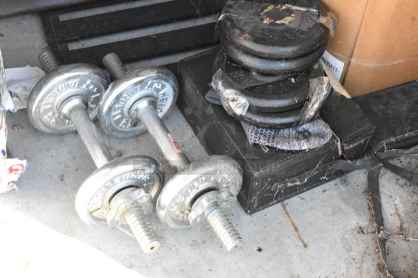 Lot of storage unit items including weight plates and metal dumbbells, minor wear visible.