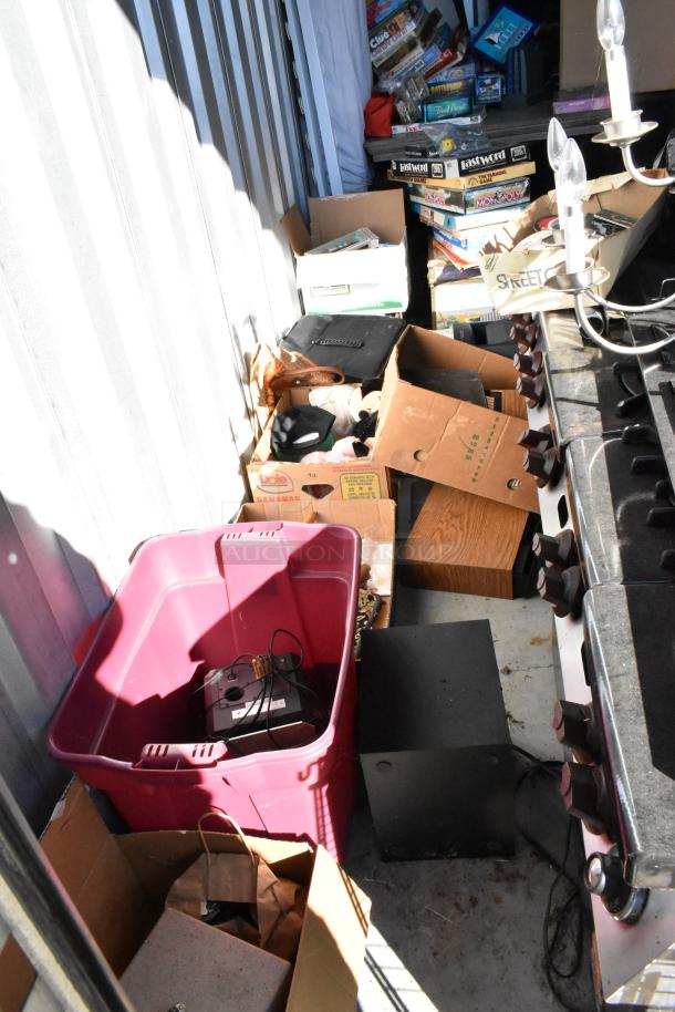 Storage unit contents including a portable grill, board games, boxes, and a chandelier. Items in used condition.