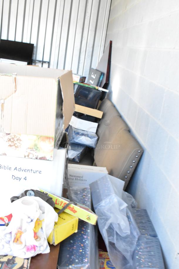 Storage unit contents with boxes and miscellaneous items, including games and decor. Unit requires full clean-out.