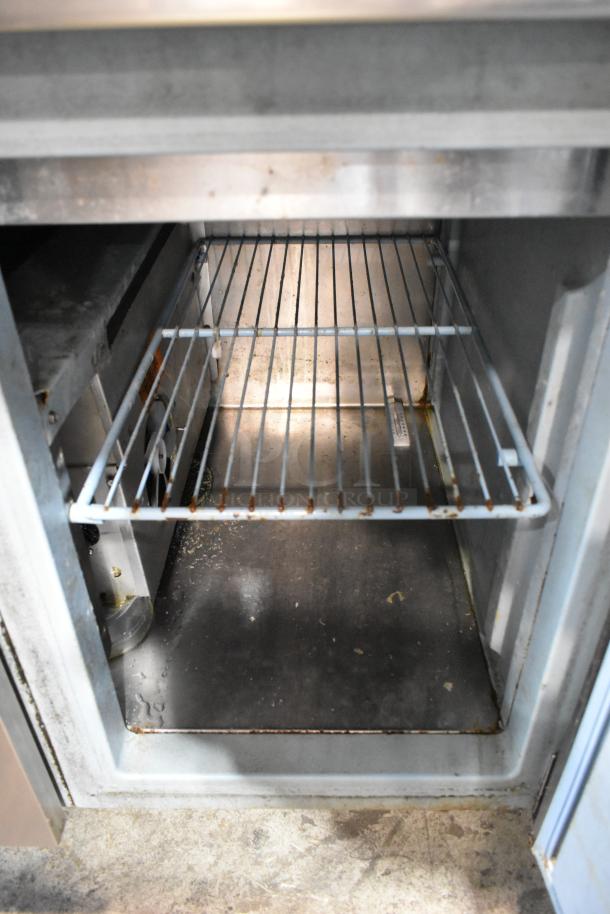 Delfield MKV9885751 stainless steel pizza prep table interior, features 2 doors, shelf, visible wear, ideal for commercial use.