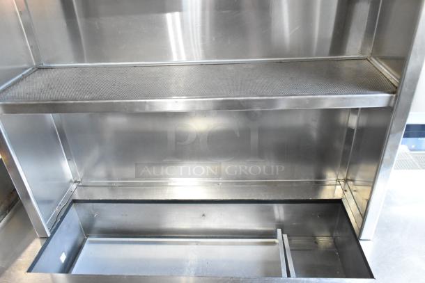 Stainless steel work station with Delfield 8146N 2-door cooler, 2 warming drawers, overshelf, and Hatco food strip warmer.