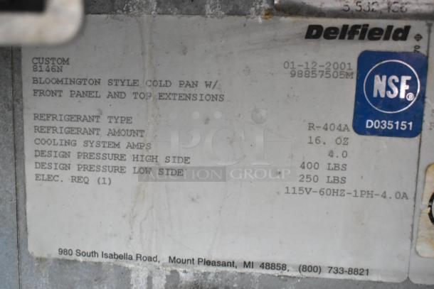 Label for Delfield 8146N cooler at stainless steel workstation, listing refrigerant type and specs; NSF certified.