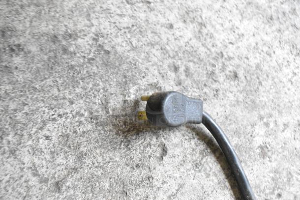 A three-pronged power plug on a textured concrete surface, part of a kitchen work station assembly.