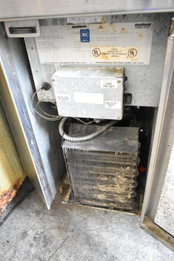 Stainless steel work station with Delfield 8146N two-door cooler, two drawers, overhead shelf, and Hatco food warmer. Used condition.