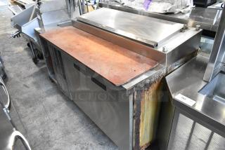 Delfield stainless steel commercial pizza prep table with sink bay, 115 volts, 1 phase, visible wear and rust on sides.