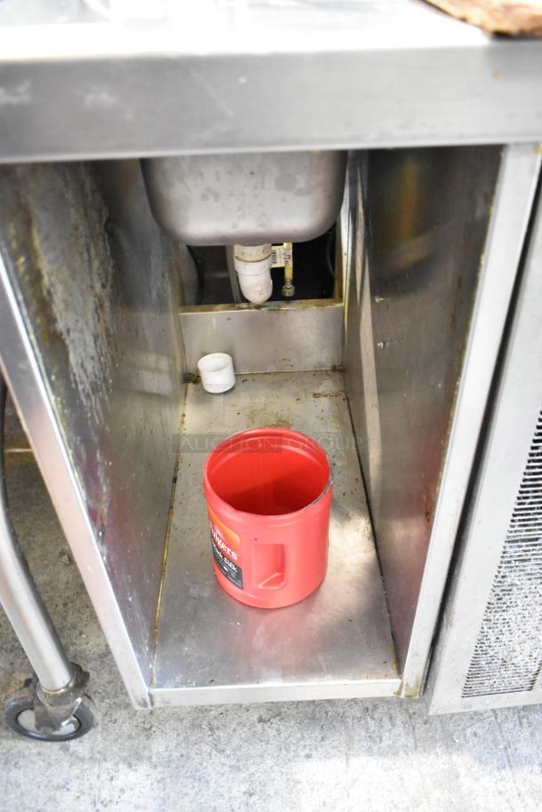 Delfield stainless steel commercial pizza prep table with sink bay, visible sink piping, and red container below. 115 Volts, 1 Phase.