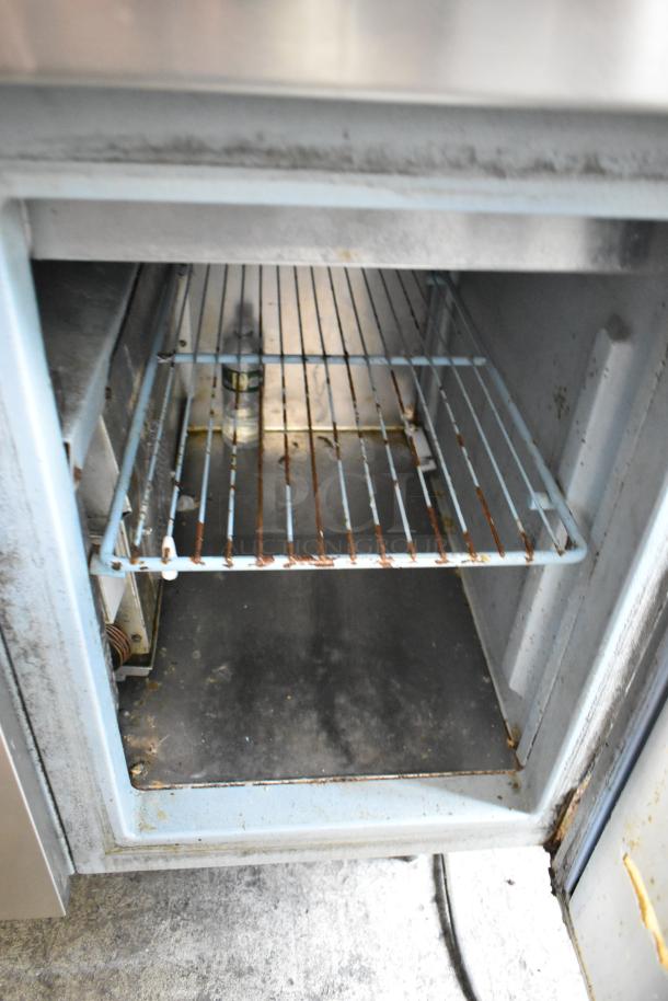 Delfield stainless steel commercial pizza prep table with sink bay, 115 volts, 1 phase. Features visible wear and rust.
