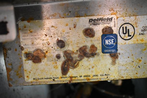 Delfield stainless steel commercial pizza prep table with sink bay, showing rust and NSF, UL labels, model details obscured.