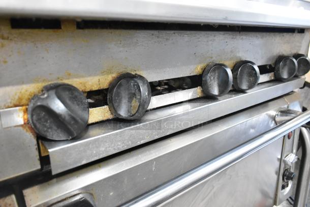 Vulcan commercial gas range with 6 burners, convection oven, 2-tier over-shelf, and backsplash on casters. Used condition.