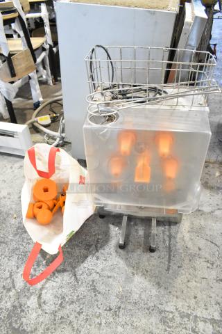 Metal commercial countertop citrus juicer with spare parts, 115 volts, 1 phase. Includes visible orange components.