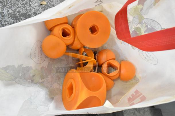 Orange spare parts for a commercial citrus juicer, featuring various shapes for assembly. Condition appears used.