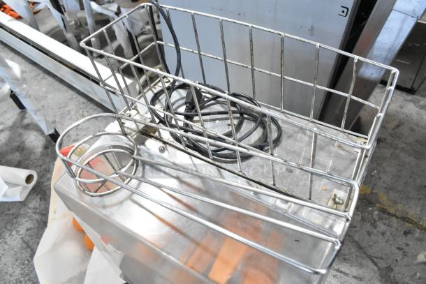 Commercial countertop citrus juicer, metal body, 115 volts, 1 phase, includes spare parts, visible power cord, used condition.