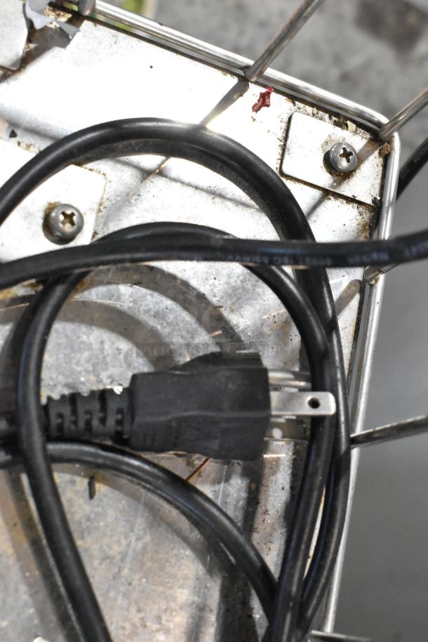 Metal commercial countertop citrus juicer with spare parts, showing power cord and metal casing. 115 volts, 1 phase.