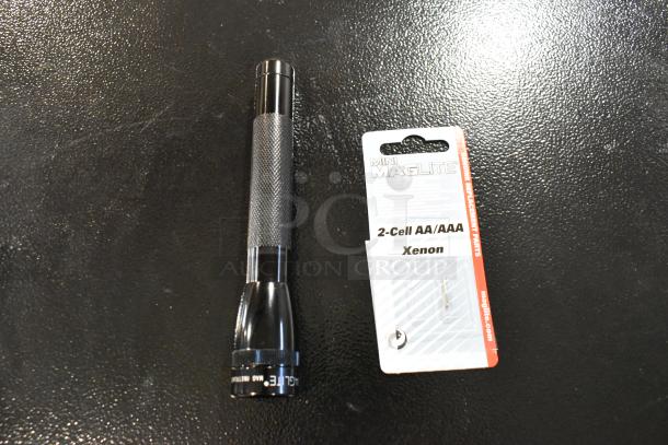 Black Maglite flashlight, 2-Cell AA/AAA, with textured grip. Includes a package of replacement Xenon bulbs.