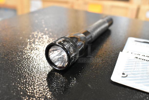 Maglite flashlight with black casing, designed for 2 Cell AA/AAA batteries, shown on a textured surface.