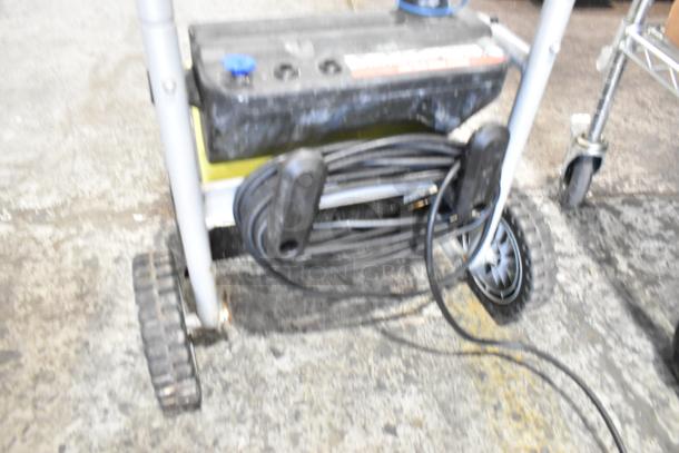 Ryobi 1700 PSI 1.2 GPM electric pressure washer with wheels, hose reel, visible wear on casing, suitable for light-duty cleaning.
