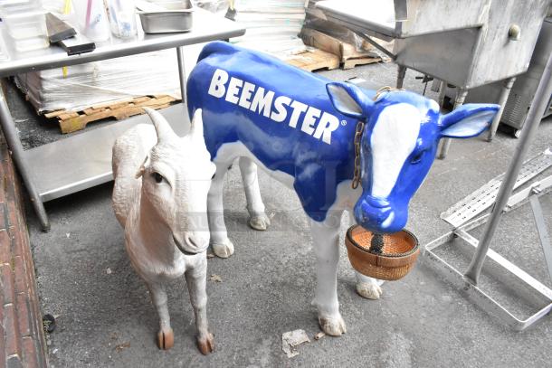 Cow and goat statues; cow painted blue with "Beemster" logo, goat in natural colors. Both in good condition.