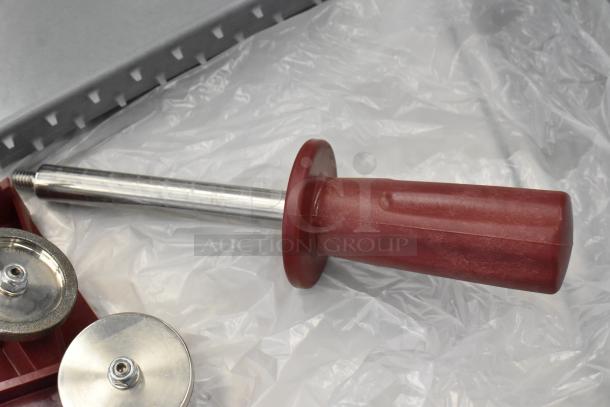 Close-up of a metal tool with a red plastic handle, likely a sharpening component for the Berkel X13-PLUS slicer.