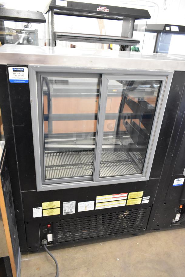 Ojeda RDCH-3 metal deli display case, 120V, commercial floor style, sliding glass doors, visible model and voltage labels.