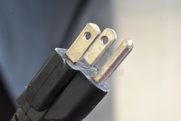 Close-up of a metal prong plug, showing wear on the brass-colored metal connectors.