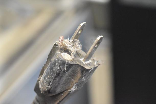 Close-up of a worn electrical plug, covered in dust and debris, from a VacMaster VP545 vacuum sealer. Condition appears neglected.