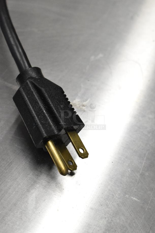 Close-up of the power plug for a 2025 Hoshizaki DCM-271BAH-OS stainless steel commercial ice dispenser. Plug shows three prongs on metallic surface.