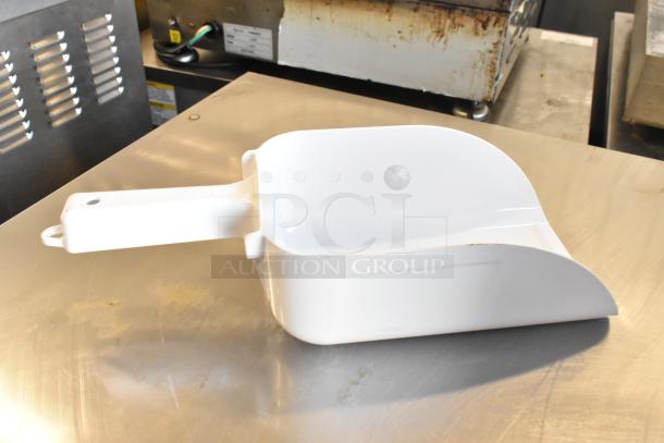 White plastic scoop with handle on a metal surface, possibly used for ice or other granular materials.