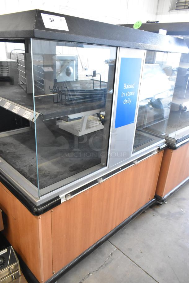 Custom Deli's Inc metal 2-tier warming display case on casters, 120-208V, 1 phase, glass doors, "Baked in store daily" sign.
