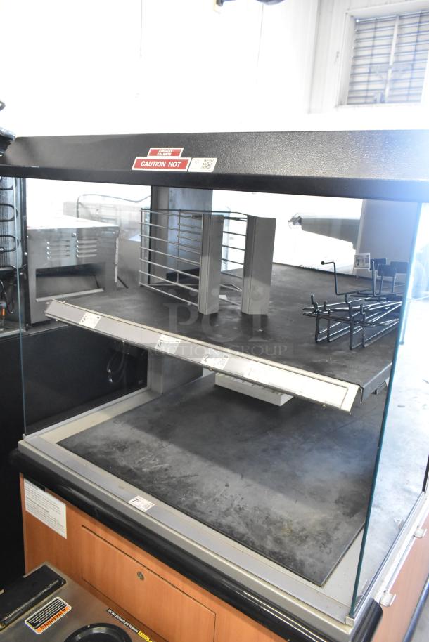 Custom Deli's Inc 2-tier metal warming display case with glass panels and commercial casters. Label indicates "Caution Hot."