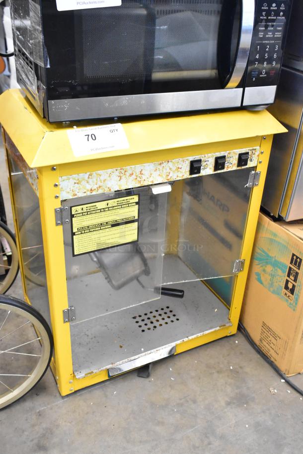 Metal commercial countertop popcorn machine, yellow frame, 115V, 1 Phase. Visible wear and instruction label inside.