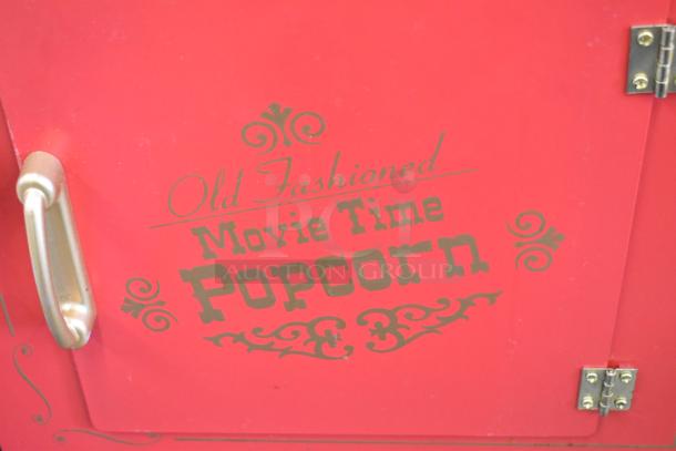 Red Nostalgia CCP510 popcorn machine cart with "Old Fashioned Movie Time Popcorn" text, metal handle, and decorative designs.