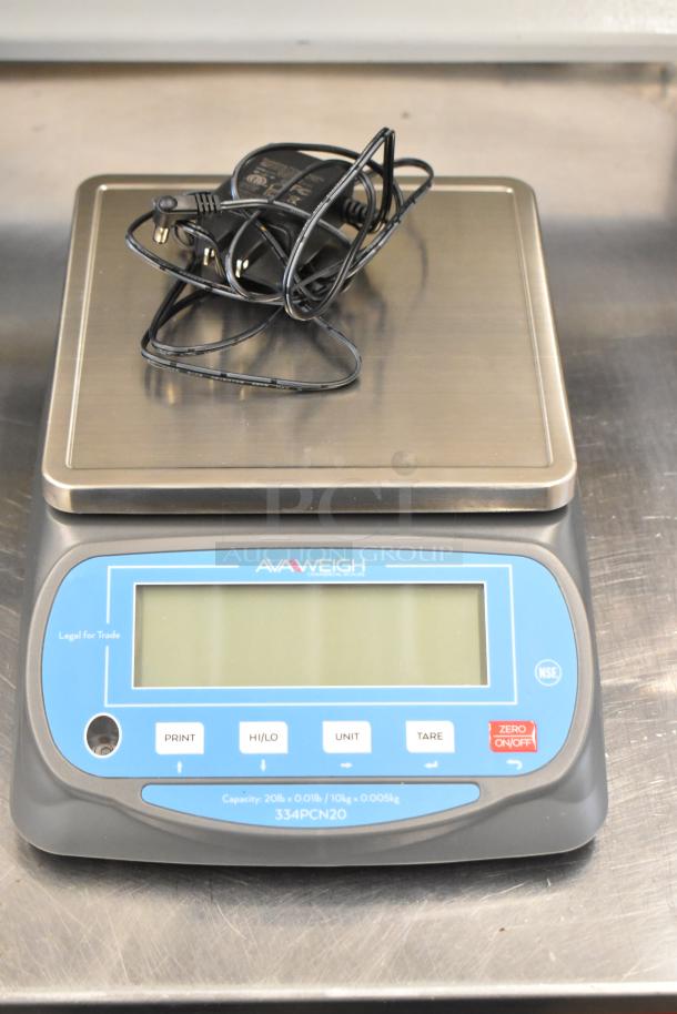 AvaWeigh 334PCN20 20 lb. portion scale with digital display, marked "Legal for Trade." New with minor scratches and charger included.