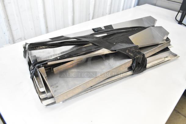 Metal panels stacked and wrapped with black tape, resting on a white surface.