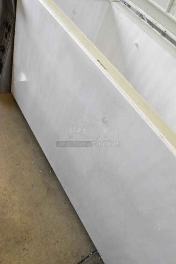 White chest freezer with hinge lid, 115 volts, 1 phase, visible scuffs on side, in good condition for auction.