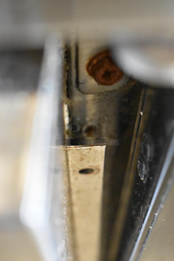 Close-up of metal frame and rusted bolt on Spartan SSGBB-60 cooler; detailing condition for auction evaluation.