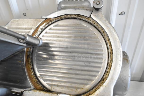 Globe 285 metal commercial meat slicer with blade sharpener, showing signs of use, 115 volts, 1 phase, countertop model.